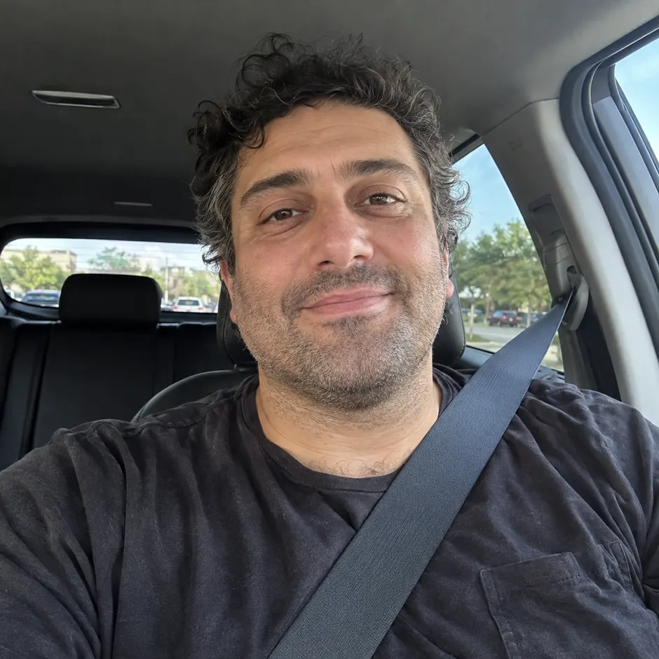AI-generated example of a demo persona today: Jordan, smiling in a selfie in his car on a lunch break.